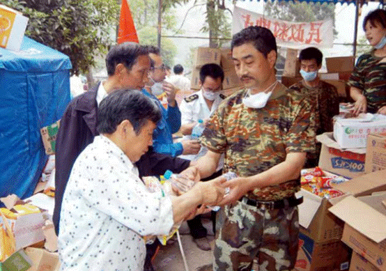 5月24日，党员、北川羌族自治县民政局局长王洪发（右三）为灾区群众分发食 品。地震夺去王洪发包括16岁儿子在内的20位亲人的性命，而他却用自己的双手刨出 10条生命（CFP 提供）.PNG